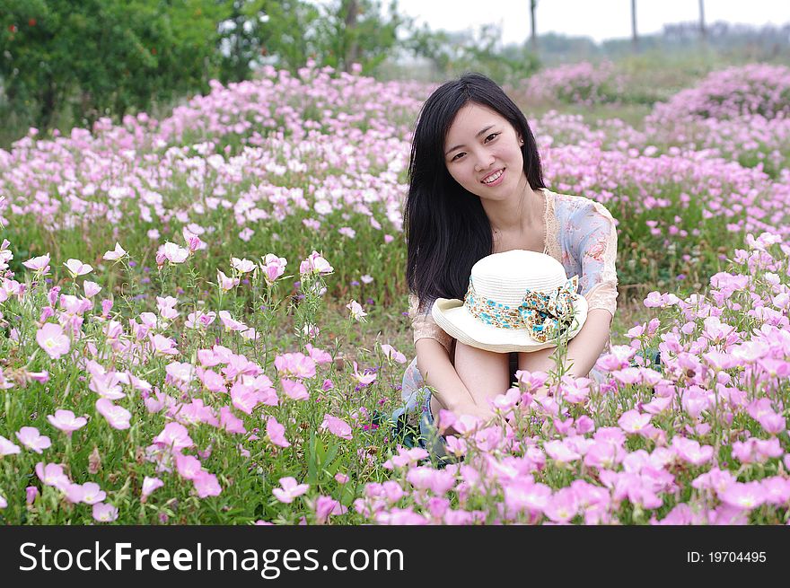 A girl is sitting in flowers and smiling. A girl is sitting in flowers and smiling