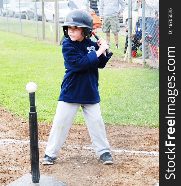 A T-Ball player at bat in a game in Salem, Oregon wearing a blue jacket, gray pants and black helmet. A T-Ball player at bat in a game in Salem, Oregon wearing a blue jacket, gray pants and black helmet.