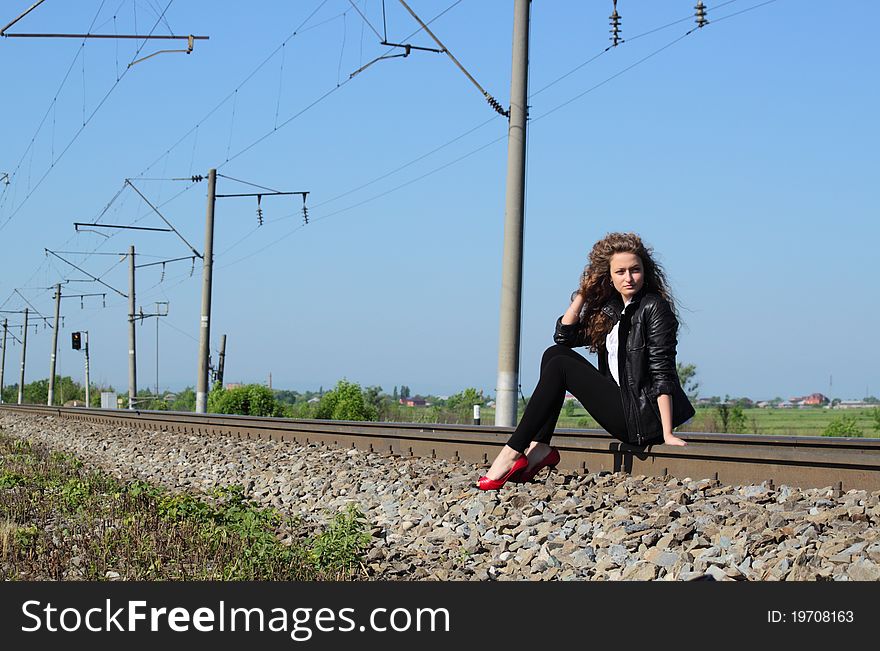 A girl sits on the rail waiting for the train. A girl sits on the rail waiting for the train