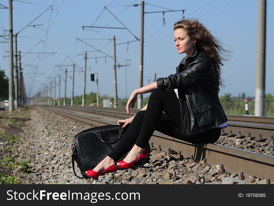 A girl sits on the rail waiting for the train. A girl sits on the rail waiting for the train