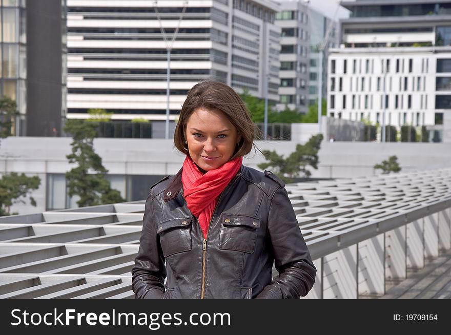 Beautiful woman in a red scarf looks into the camera. Urban scene. Portrait.