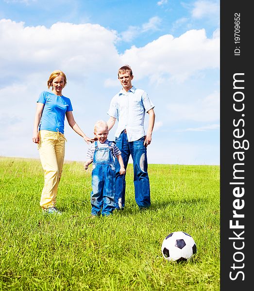 Happy young family playing football outdoor on a summer day