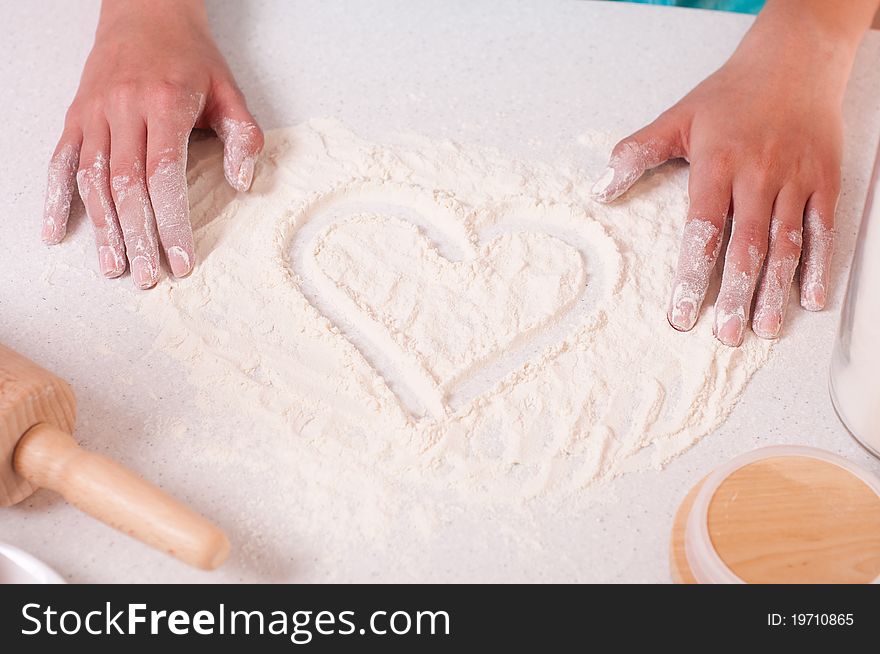 Heart shape on flour, done by woman hands.