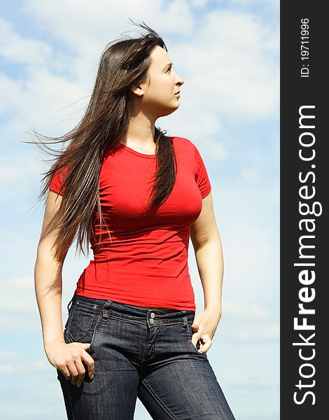 Young brunette woman in red shirt looking at side, sky with clouds. Young brunette woman in red shirt looking at side, sky with clouds