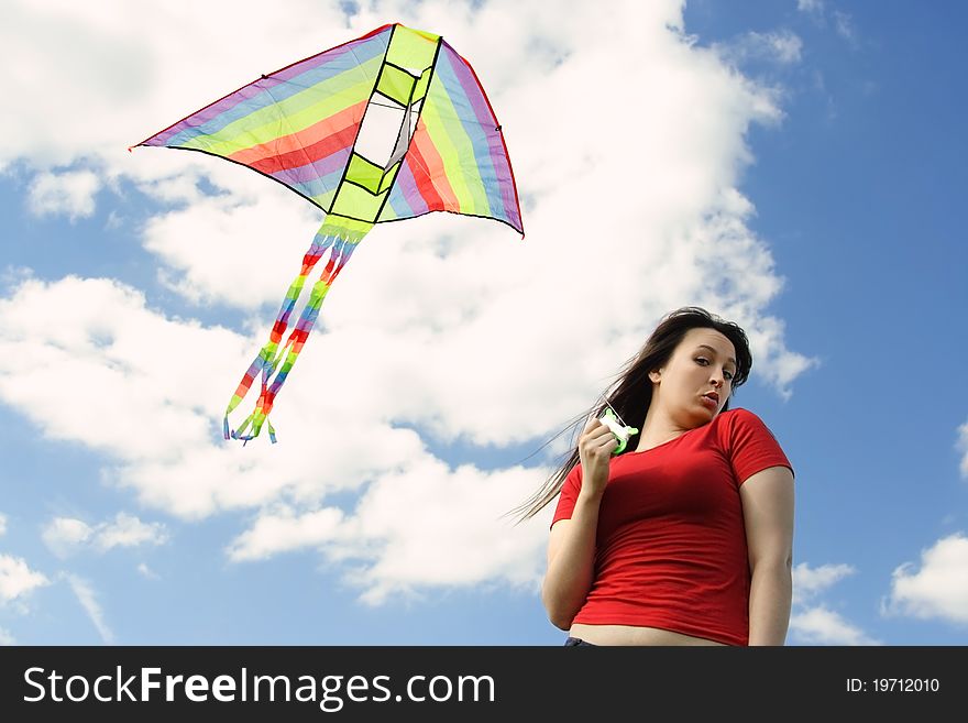 Young girl in red shirt flying kite, blue sky