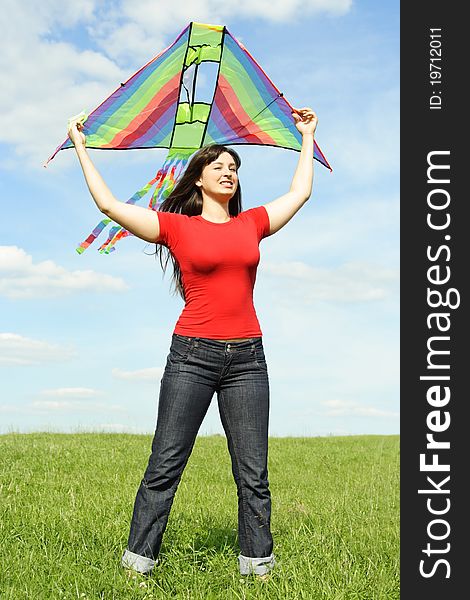 Young girl in red shirt standing on summer meadow and holding kite above head. Young girl in red shirt standing on summer meadow and holding kite above head