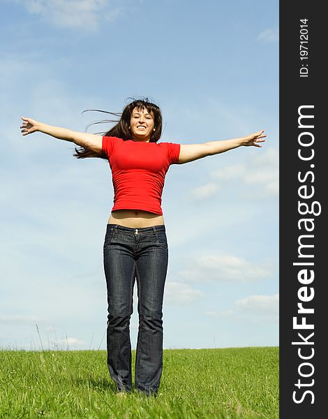 Young girl in red shirt standing on summer meadow, hands apart, blue sky. Young girl in red shirt standing on summer meadow, hands apart, blue sky