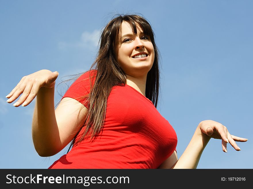 Young girl in red shirt making gesture, blue sky