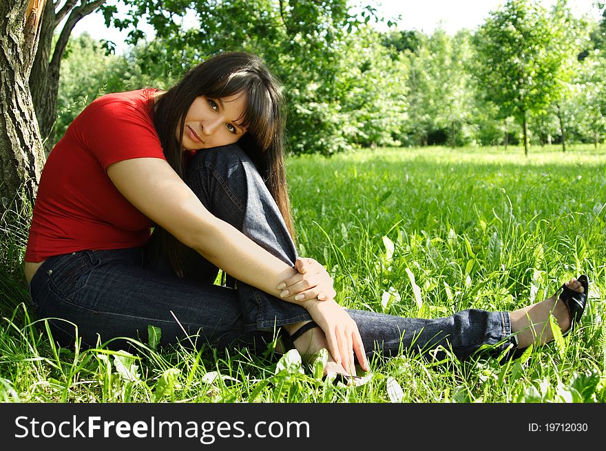 Girl in red shirt siting near tree