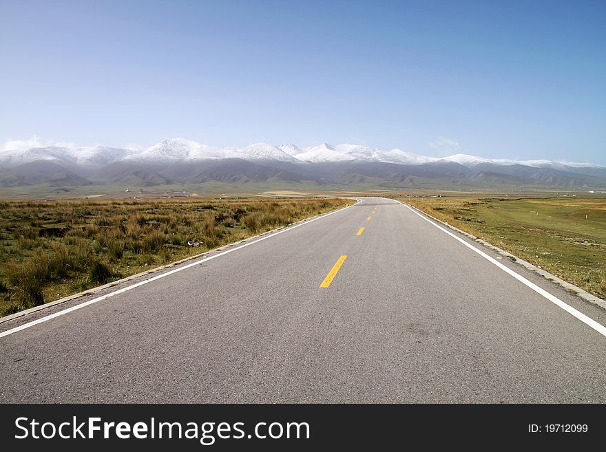 Straight road full of snow mountain