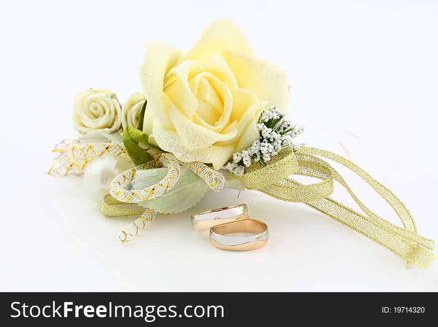 A pair of wedding rings lying next to small bouquet. A pair of wedding rings lying next to small bouquet