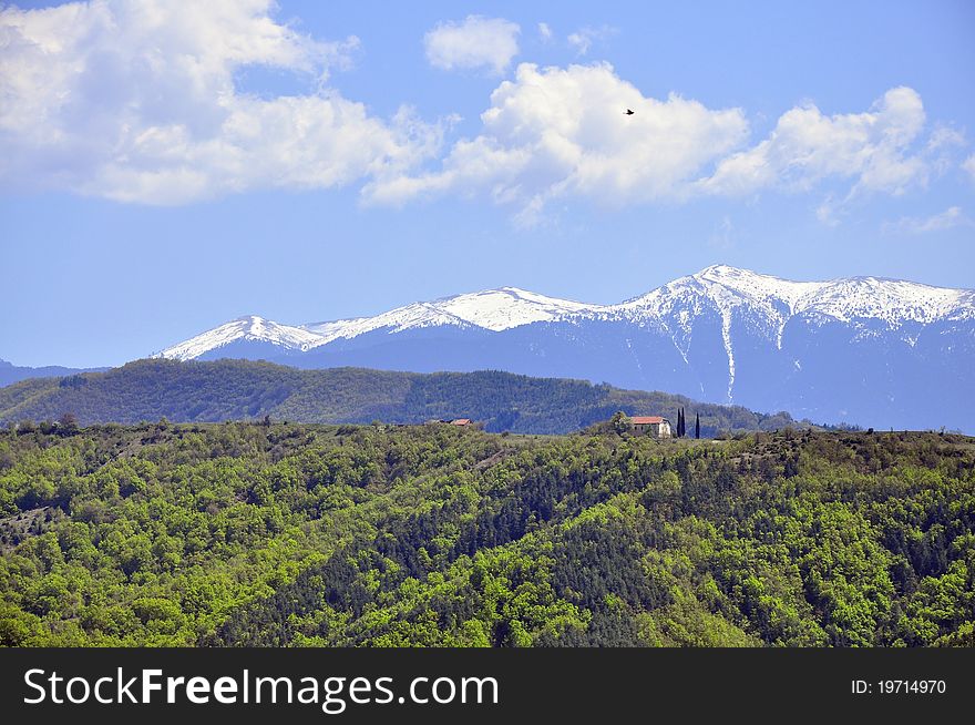 Snowy mountain top and far chalet over the green forest. Snowy mountain top and far chalet over the green forest