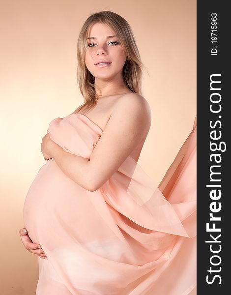 Beautiful pregnant blond woman in beige wraped tissue. Beautiful pregnant blond woman in beige wraped tissue