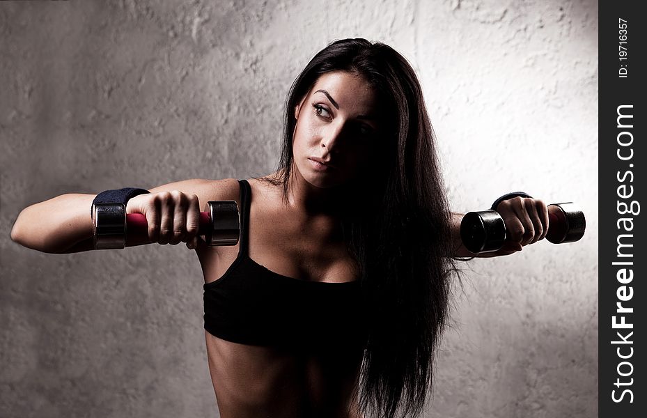 Beautiful sporty muscular woman with two dumbbell in the gym. Beautiful sporty muscular woman with two dumbbell in the gym