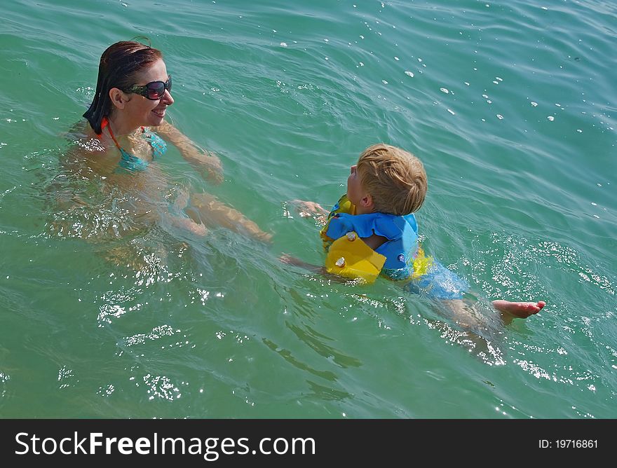 Happy family of mother with kid in the ocean waves. Happy family of mother with kid in the ocean waves