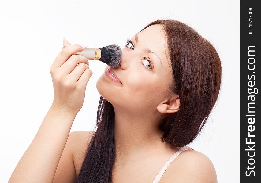 Beautiful young brunette woman applying powder with a brush