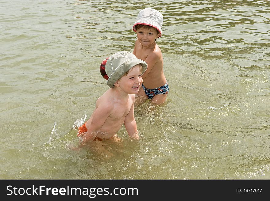 Two brothers playing with ball in the water. Two brothers playing with ball in the water