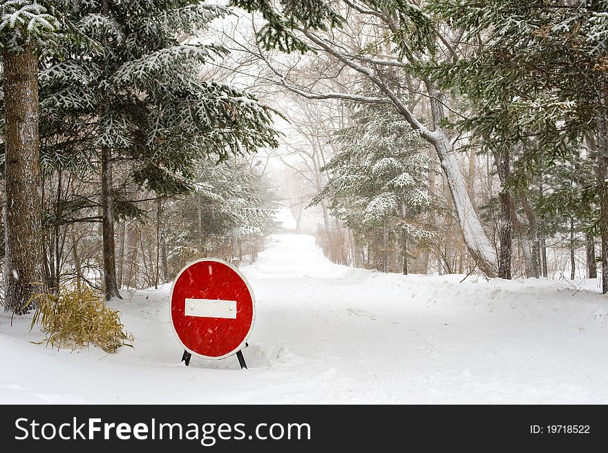 Stop Sign on winter forest Road under snowfall