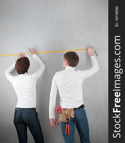 Couple measuring wall for home redecorating