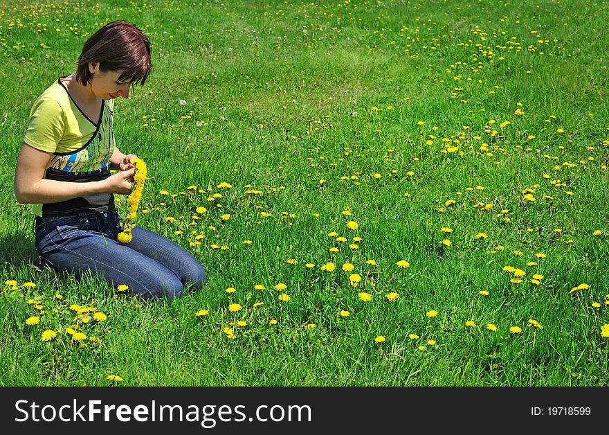 Girl resting on the green meadow with dandelion flowers