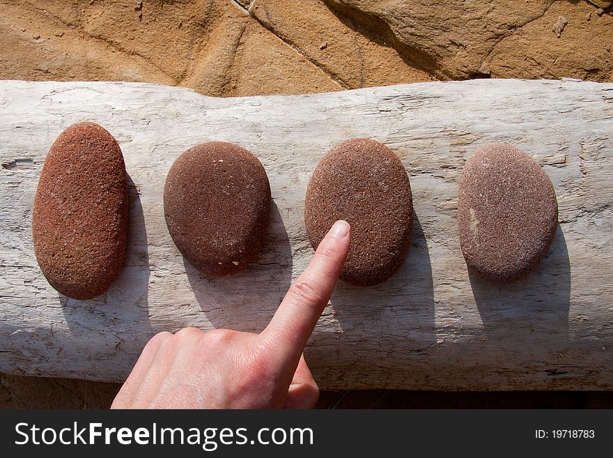 A hand indicating one stone on a row of four. A hand indicating one stone on a row of four