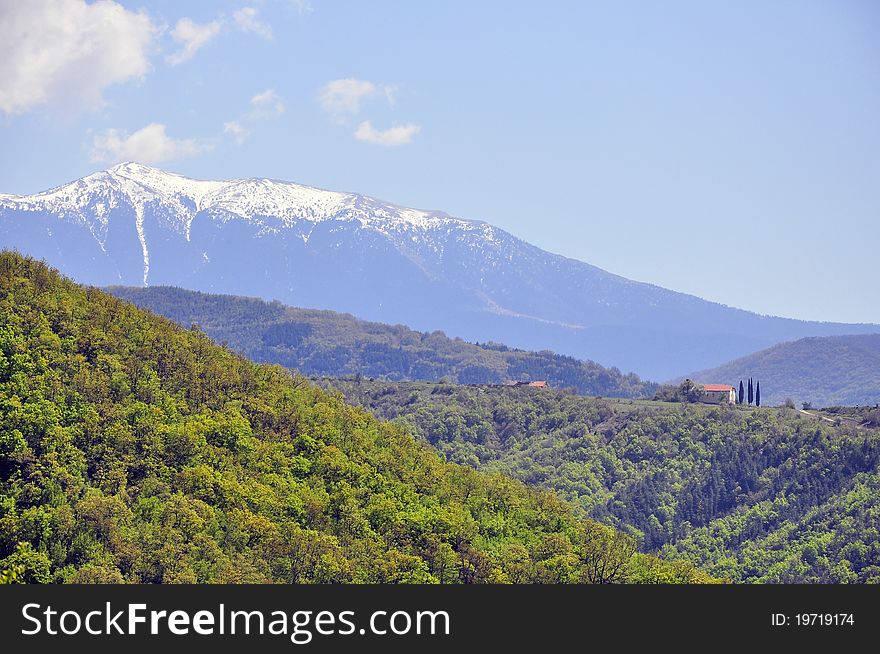 Snowy mountain top and far chalet over the green forest. Snowy mountain top and far chalet over the green forest