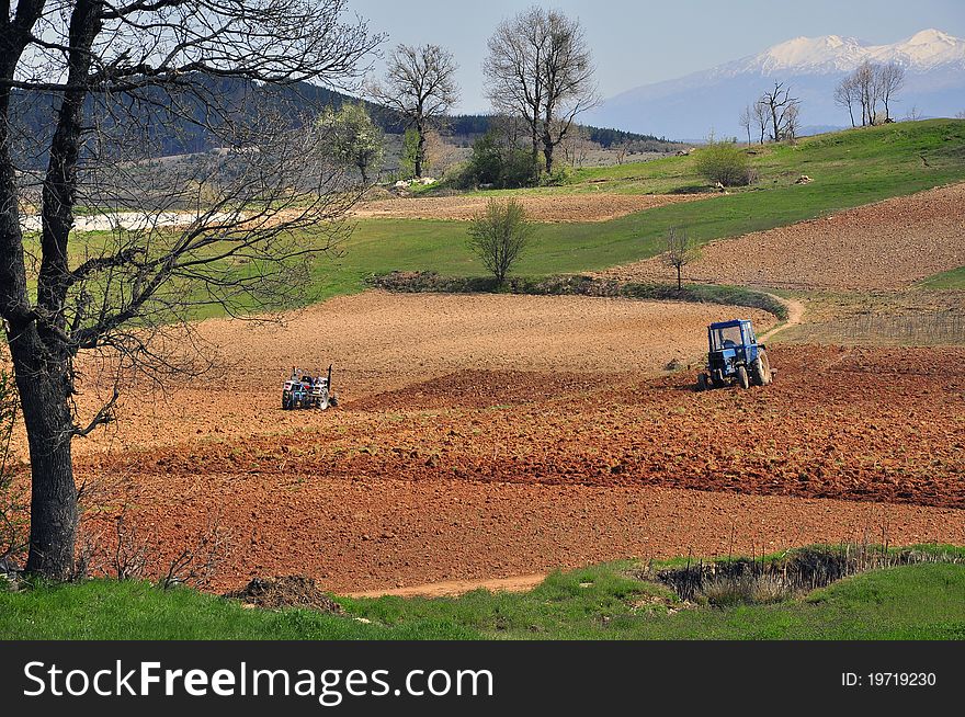 Two tractors plowing the field area