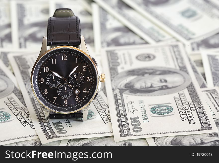 Nice modern wristwatch standing on background made from one hundred dollar notes. Nice modern wristwatch standing on background made from one hundred dollar notes