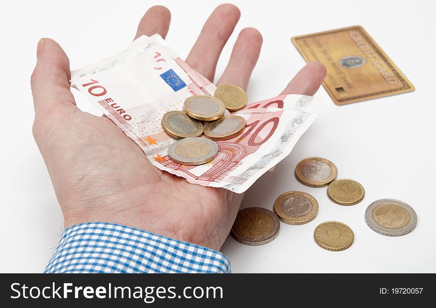 Male hand holding several Euros in his hand. In the background there is a credit card. Male hand holding several Euros in his hand. In the background there is a credit card.