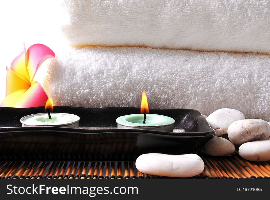 Two candles and white towel on bamboo mat.