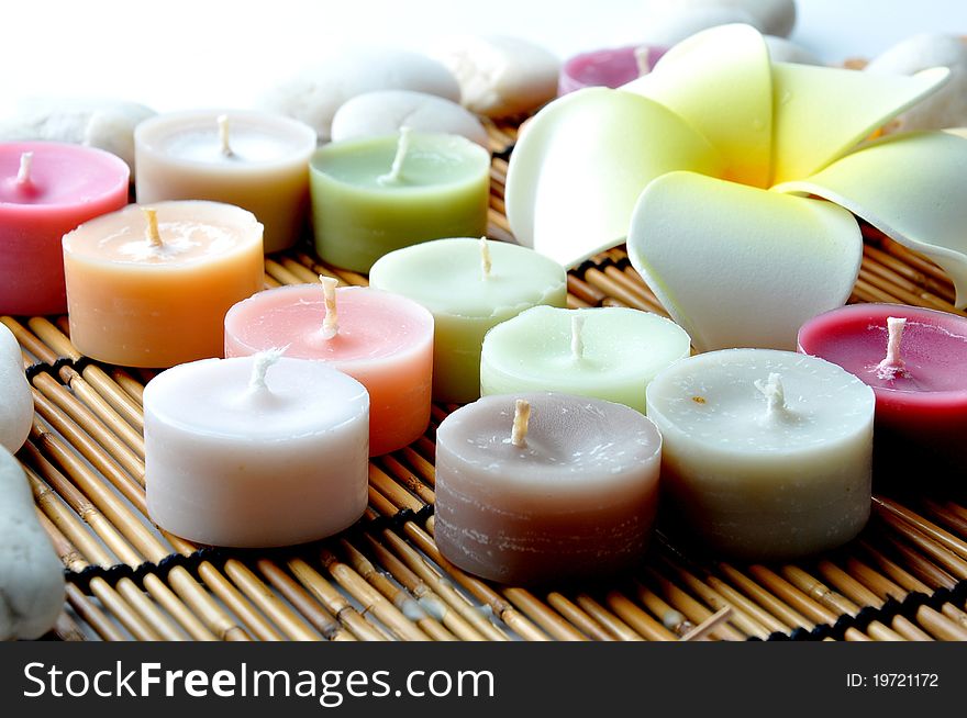 Colourful candles and stones on bamboo mat