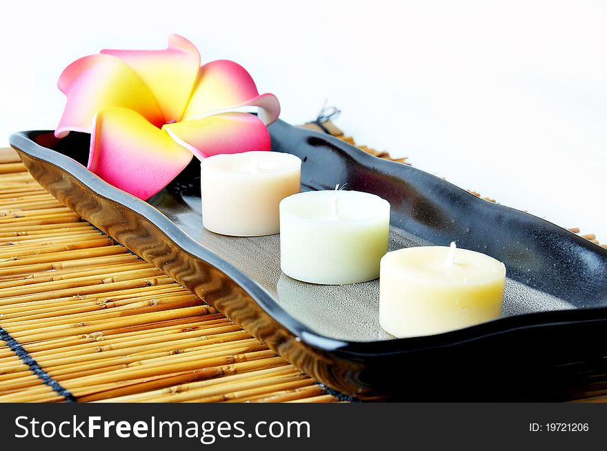 Three candles and plumeria in plate on bamboo mat. Three candles and plumeria in plate on bamboo mat