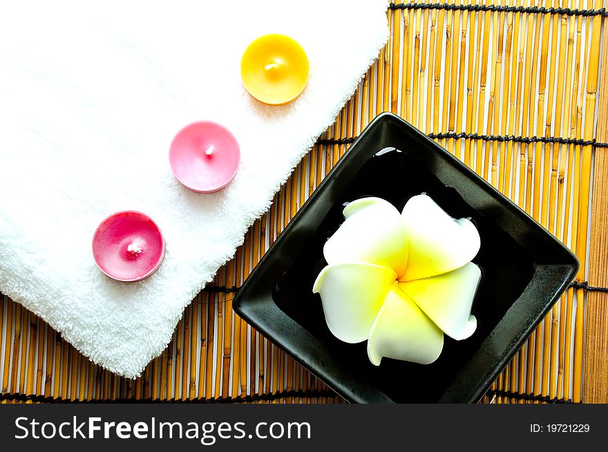 Three candles on white towel and plumeria on the plate