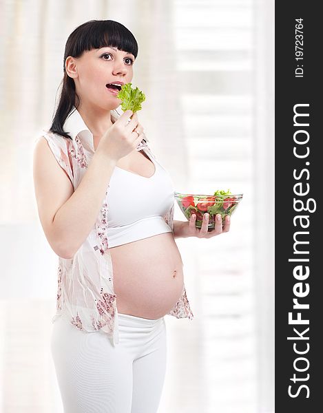 Pregnant woman with a plateful of salad in kitchen