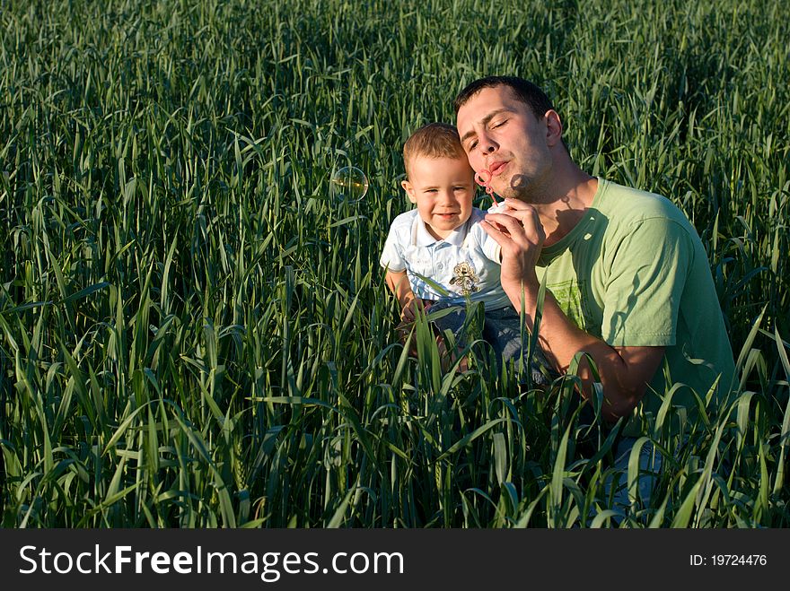 Dad and son are blowing bubbles. Dad and son are blowing bubbles