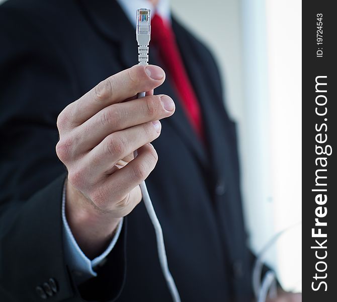 Young businessman holding an ethernet cable - stressing the importance of fast and reliable internet connection for a business (color toned image; shallow DOF)