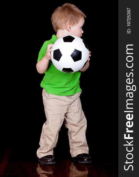 A cute child poses with his soccer ball. A cute child poses with his soccer ball.