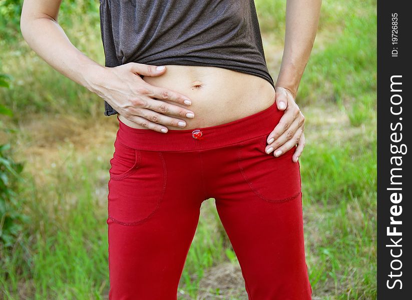 Slim woman stomach in red sports clothes outdoors