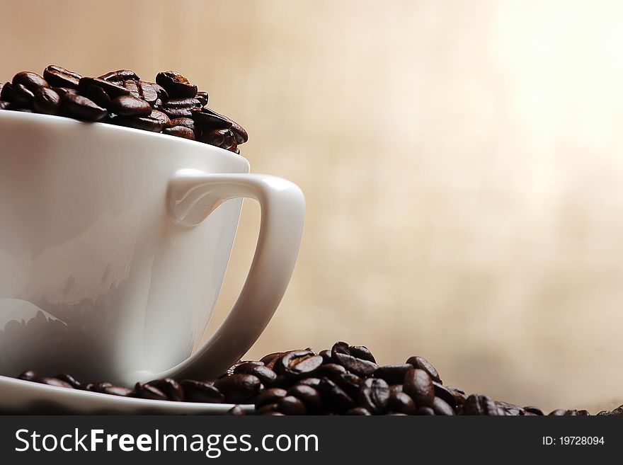 Cup of coffee with beans on yellow background