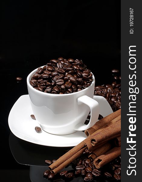 Cup with coffee beans on dark background