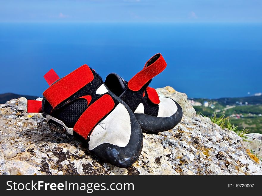 Climbing shoes on a rock with blue sea