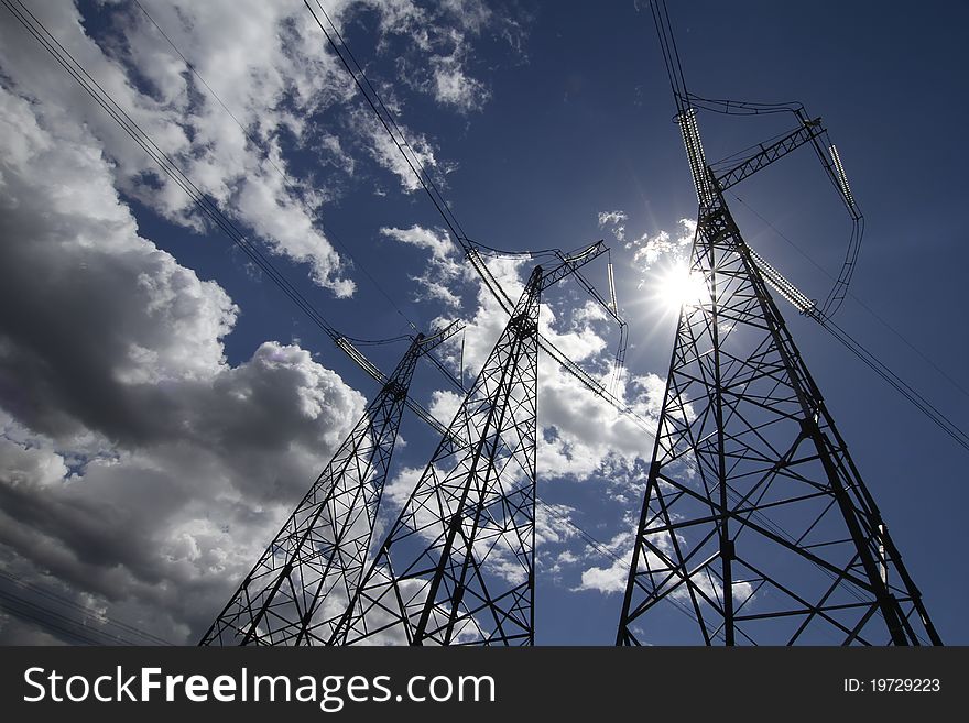 Wide angle view of high voltage power pylons on against sky. Wide angle view of high voltage power pylons on against sky