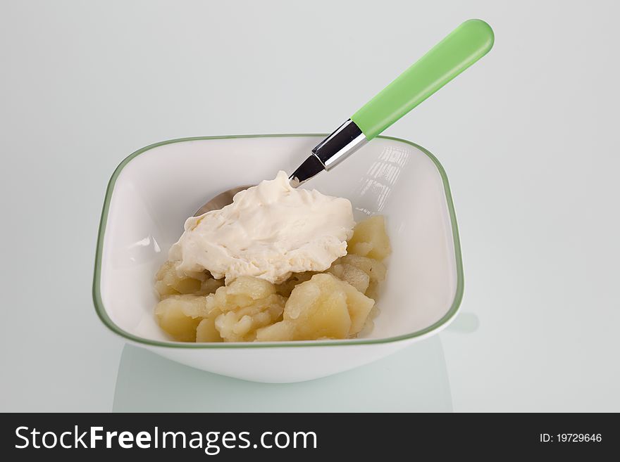 A bowl of stewed apples and cream on an isolated background.