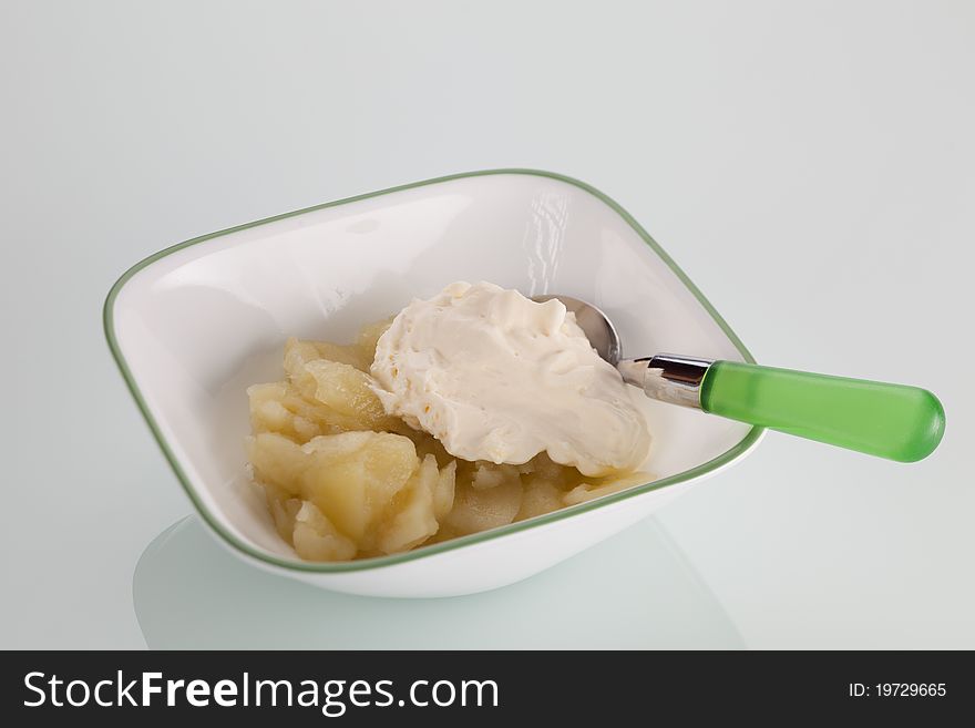 A bowl of stewed apples and cream on an isolated background.