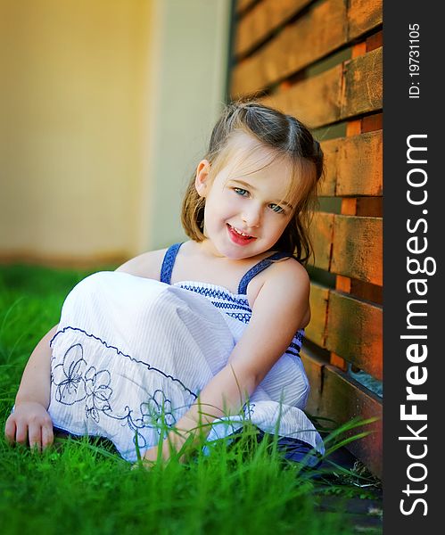 A sweet 4 year old is looking happily at the camera. She is leaning against a red timber wall. She looks relaxed and happy. A sweet 4 year old is looking happily at the camera. She is leaning against a red timber wall. She looks relaxed and happy.