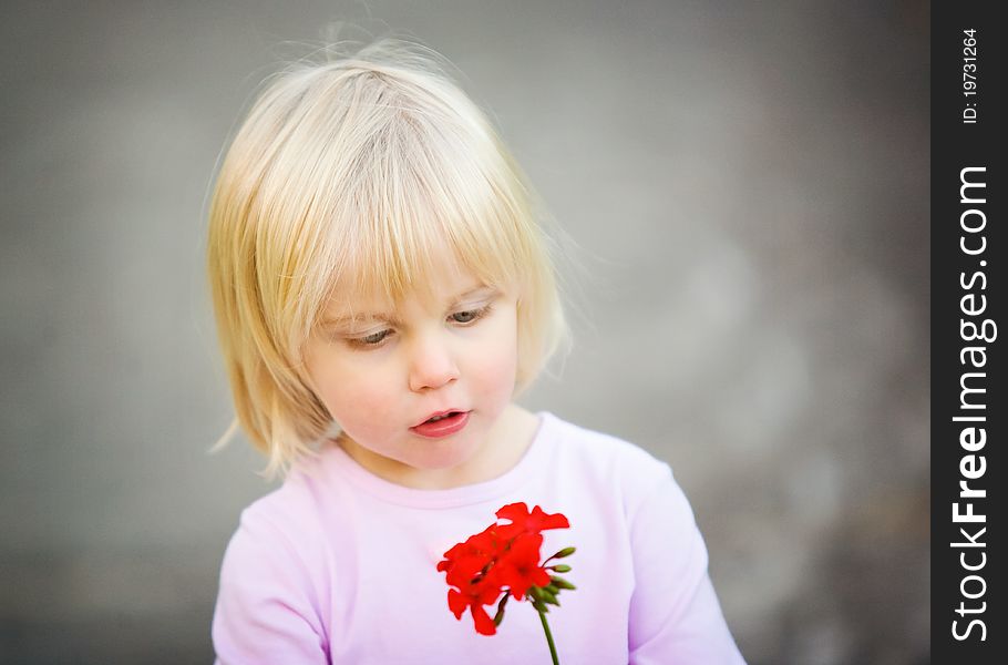 Cute little girl looking at her red flower