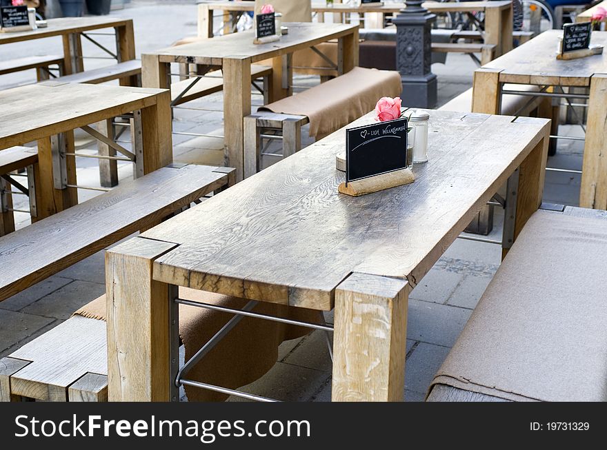 Table decoration outside in a street at a rustically restaurant with heavy, wooden tables and benches. Table decoration outside in a street at a rustically restaurant with heavy, wooden tables and benches