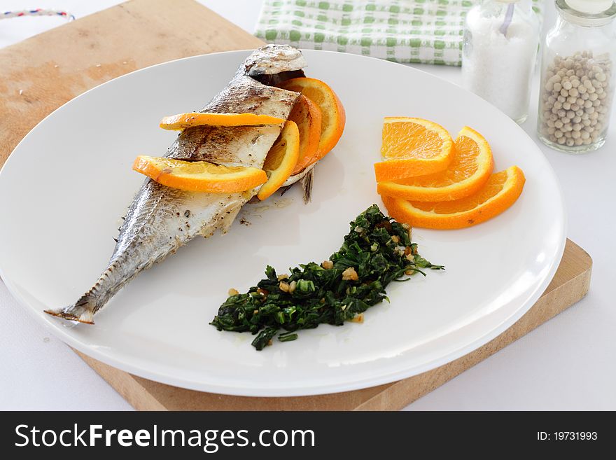 A plate of Torpedo Scad/mackerel scad fish served with sliced oranges, parsley and salsa verde. A plate of Torpedo Scad/mackerel scad fish served with sliced oranges, parsley and salsa verde