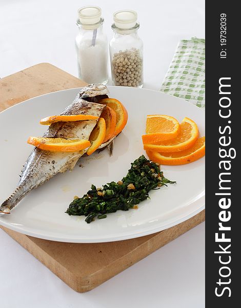 A plate of Torpedo Scad/mackerel scad fish served with sliced oranges, parsley and salsa verde. A plate of Torpedo Scad/mackerel scad fish served with sliced oranges, parsley and salsa verde