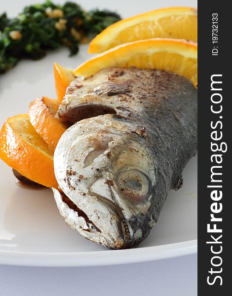 Close-up of a plate of Torpedo Scad/mackerel scad fish served with sliced oranges, parsley and salsa verde. Close-up of a plate of Torpedo Scad/mackerel scad fish served with sliced oranges, parsley and salsa verde